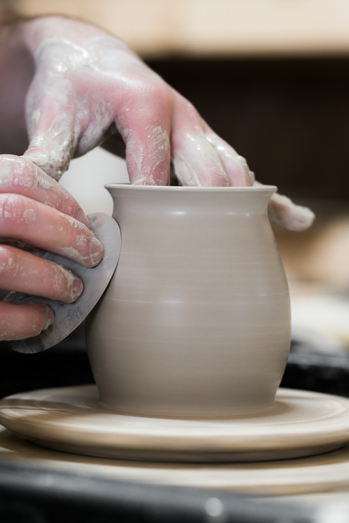Hands shaping clay on a pottery wheel
